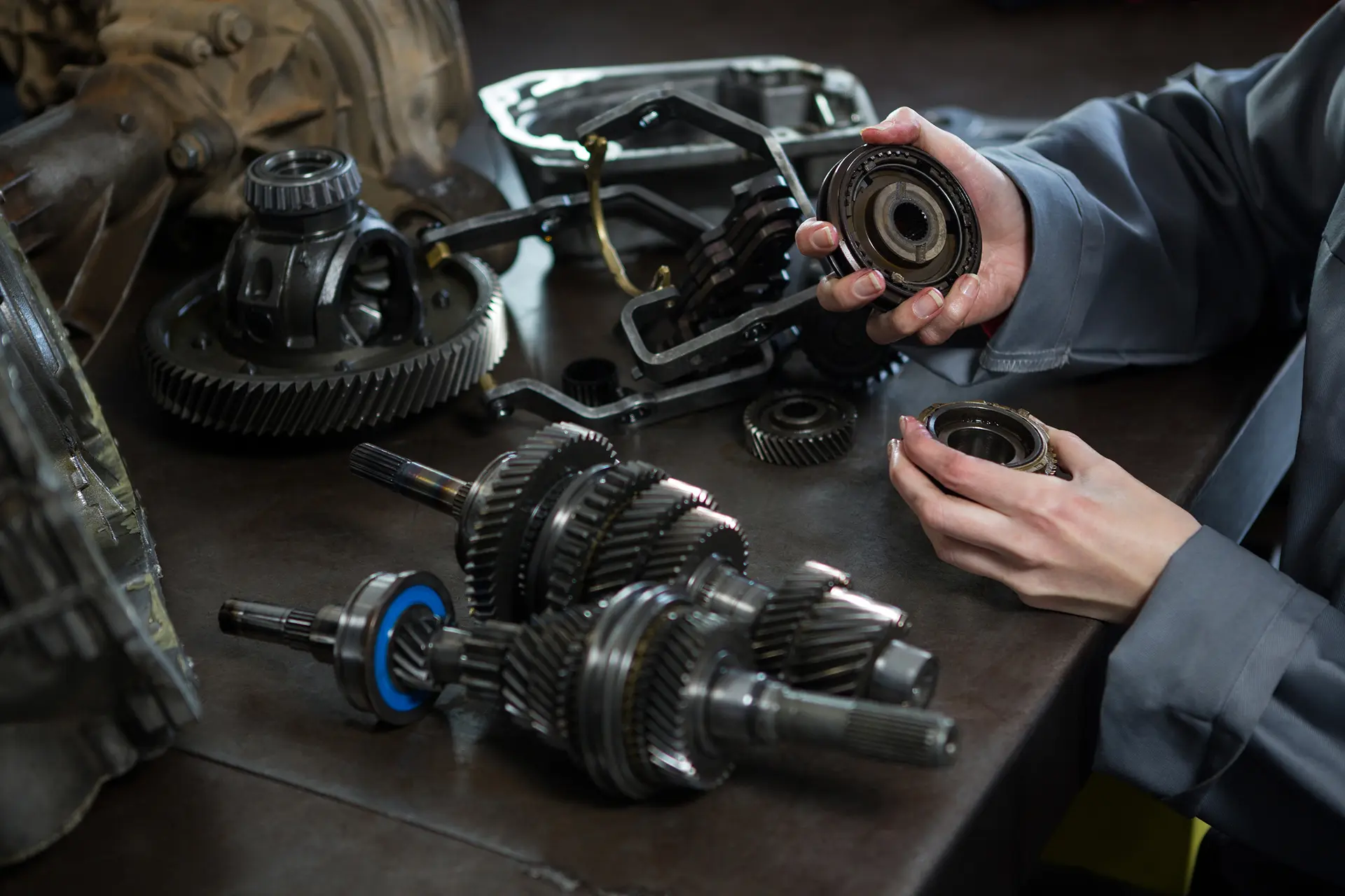 Hands inspecting automotive drivetrain gears and bearings on a workbench